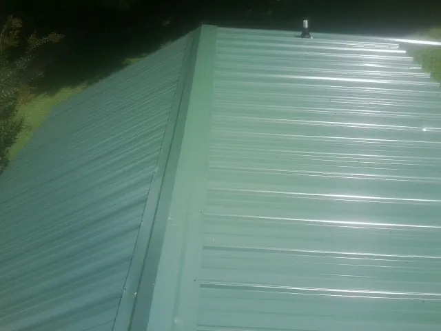 New green metal panels meeting at the ridge of a roof — Flat Roof Repair work by our crew in Wentworth
