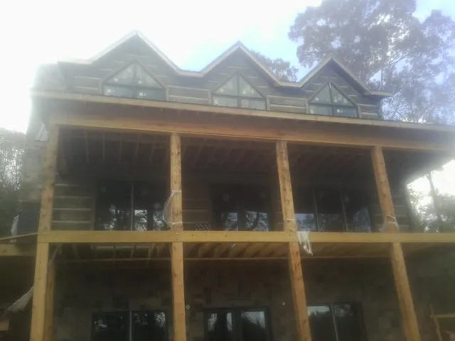 Dormers and porch framing on a large log home under construction — Roof Coating work by our crew in Wentworth